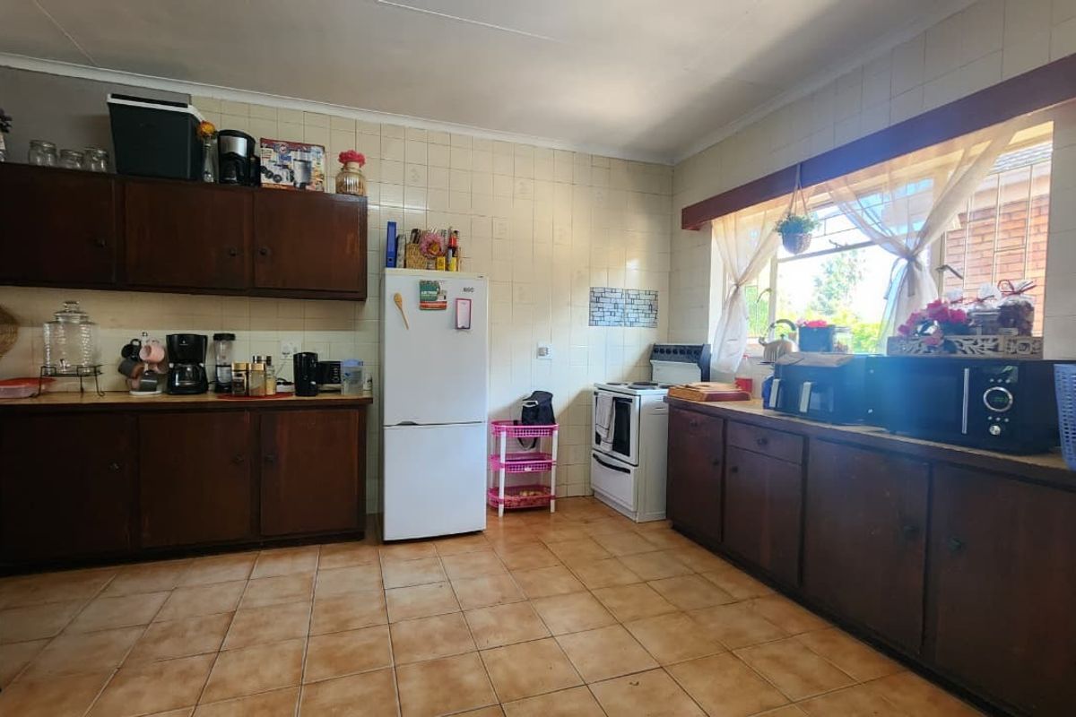 A functional kitchen featuring dark wood cabinetry, tiled walls and flooring, and a large window providing natural light.