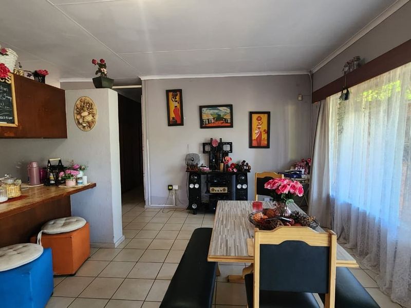 Open-plan living and dining area featuring tiled flooring, a breakfast bar with built-in cabinetry, and a large window allowing natural light.