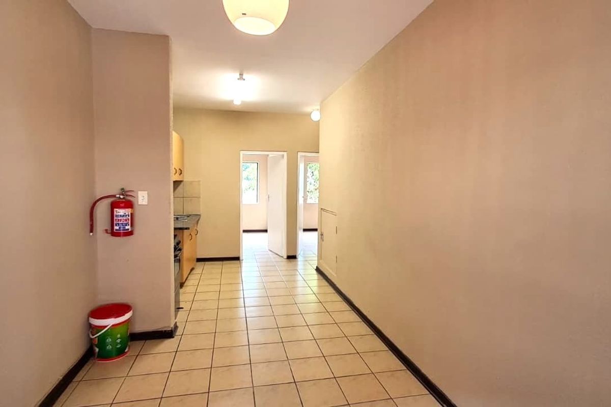 An empty kitchen area featuring tiled flooring, built-in cabinetry, and neutral wall finishes, providing a functional space ready for updates.