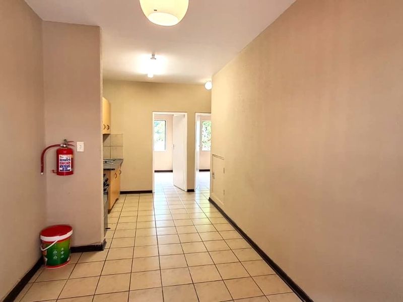 An empty kitchen area featuring tiled flooring, built-in cabinetry, and neutral wall finishes, providing a functional space ready for updates.