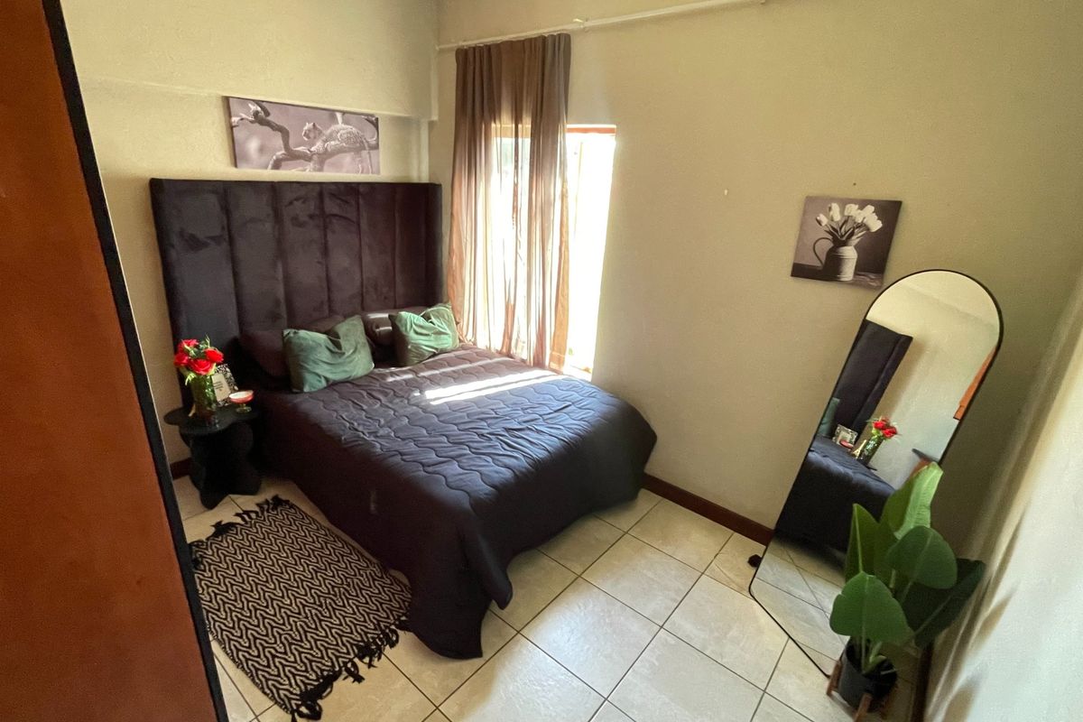 A cozy bedroom featuring tiled flooring and a window with installed curtain rails, providing a functional and comfortable living space.