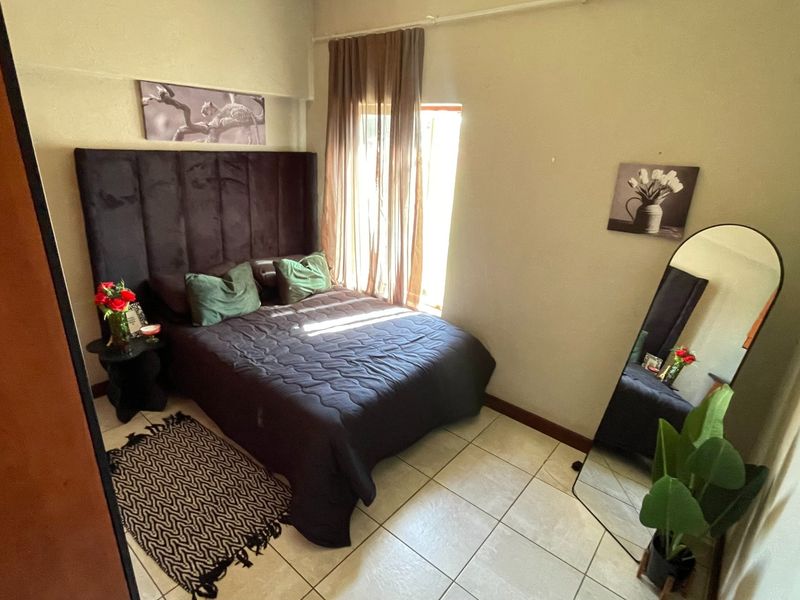 A cozy bedroom featuring tiled flooring and a window with installed curtain rails, providing a functional and comfortable living space.