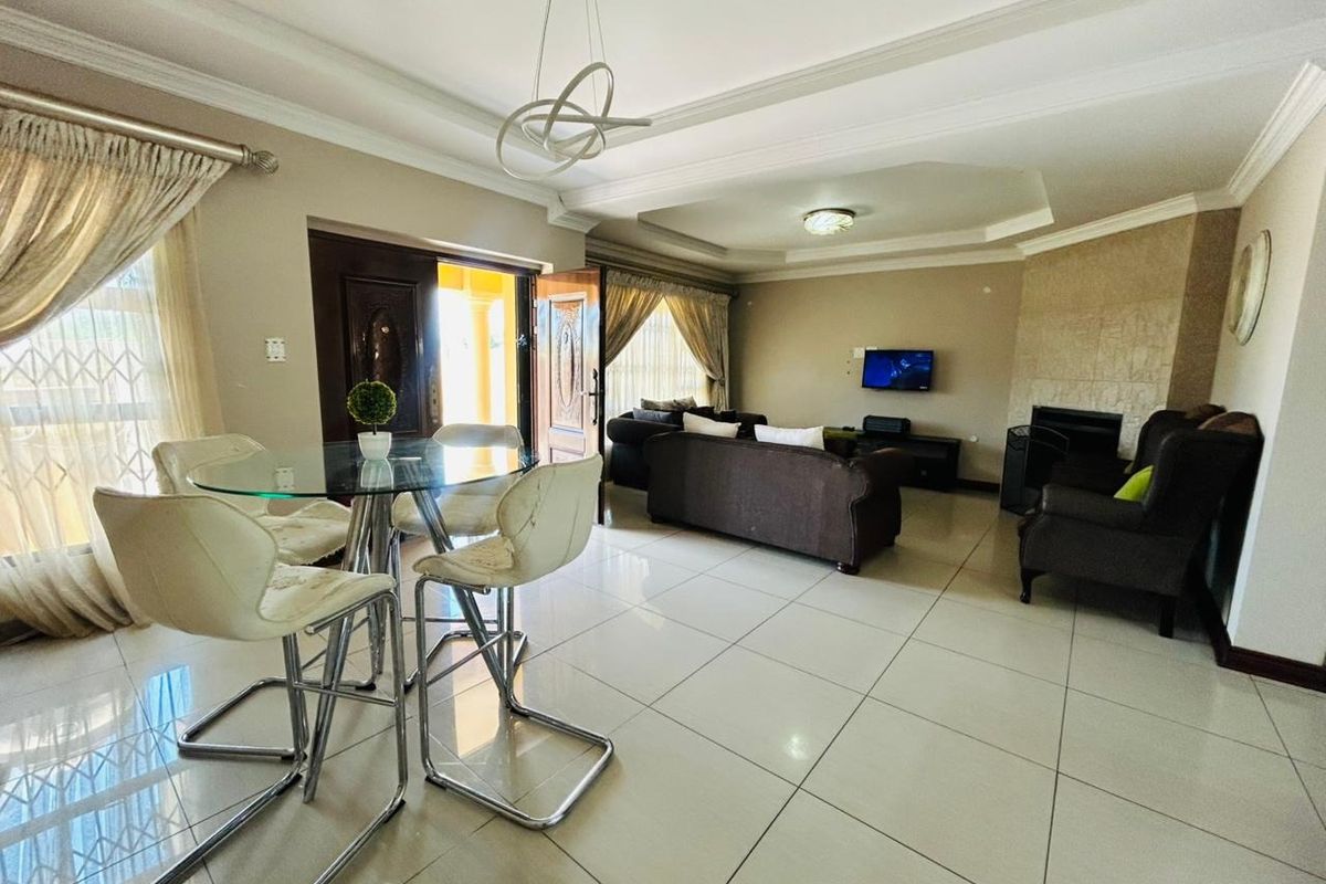 Spacious living area featuring tiled flooring, a tray ceiling with recessed lighting, and a built-in fireplace, offering a comfortable and functional layout.