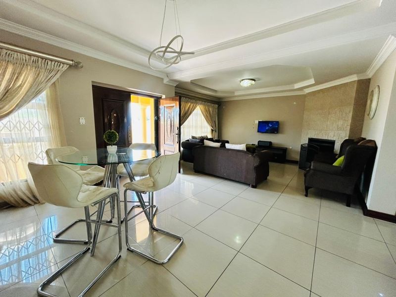 Spacious living area featuring tiled flooring, a tray ceiling with recessed lighting, and a built-in fireplace, offering a comfortable and functional layout.