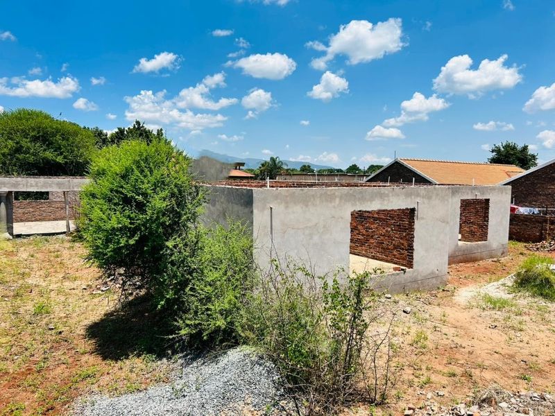 A view of a residential property under construction, featuring exposed brick walls and cement plastering on a vacant plot.