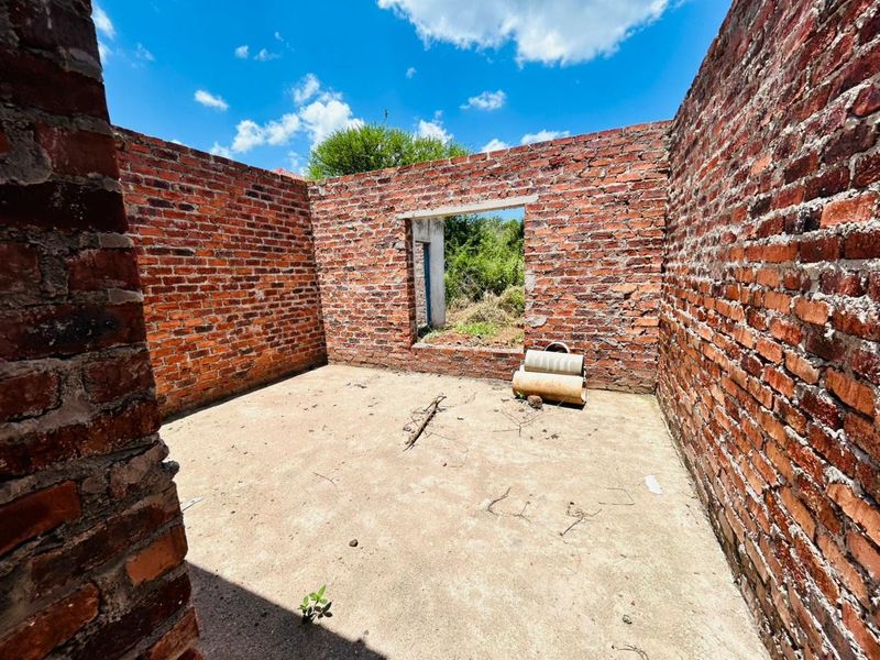 An unfinished room structure featuring exposed brick walls and a concrete floor, representing a blank canvas for residential development.