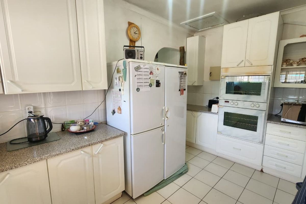 A functional kitchen featuring white cabinetry, tiled flooring, a built-in double oven, and ample counter space, offering a classic layout ready for modern updates.