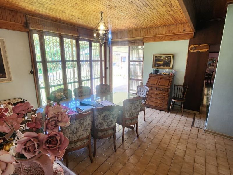 A dining room featuring a timber tongue and groove ceiling, ceramic tiled flooring, and large sliding glass doors providing access to the exterior.