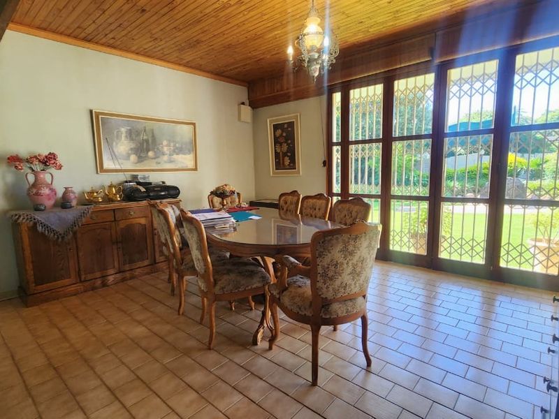 A dining room featuring a timber ceiling, tiled flooring, and large glass sliding doors that provide natural light and access to the garden.