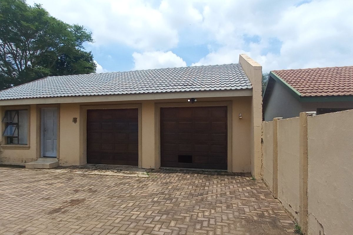 A detached double garage featuring a tiled roof, paved driveway, and perimeter walling, showing signs of exterior wear.
