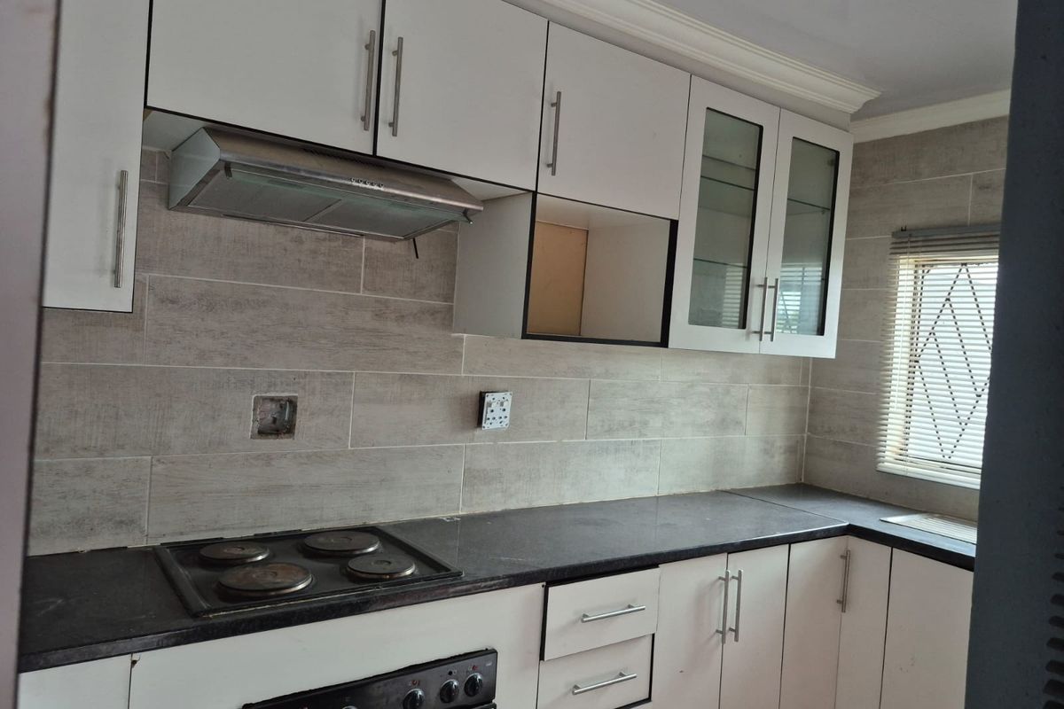 A functional kitchen featuring white cabinetry, dark stone countertops, a built-in oven and hob, and a tiled backsplash.