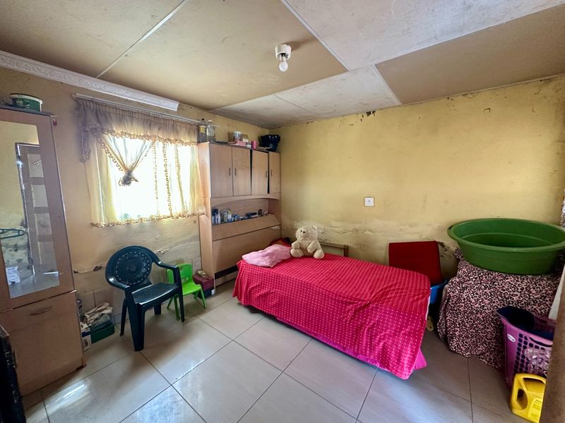 A bedroom featuring tiled flooring and a built-in cupboard, currently requiring significant cosmetic updates to the walls and ceiling.