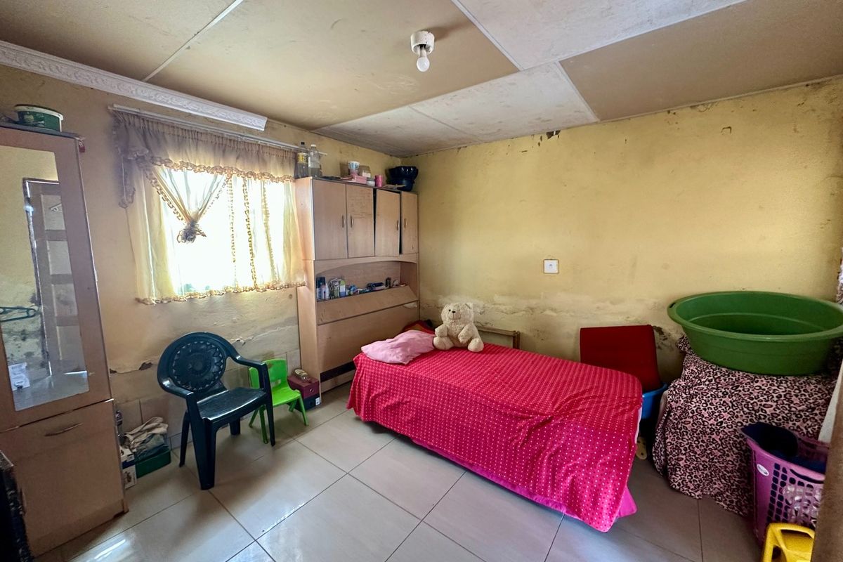 A bedroom featuring tiled flooring and a built-in cupboard, currently requiring significant cosmetic updates to the walls and ceiling.