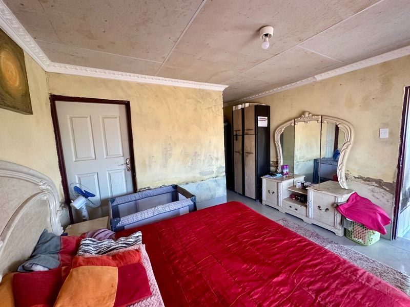 A bedroom featuring tiled flooring and ceiling cornicing, currently requiring significant wall and ceiling maintenance and cosmetic updates.