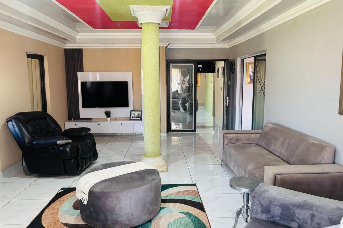 Spacious living room featuring polished tile flooring, a central structural column, and a custom built-in media unit with a recessed ceiling design.