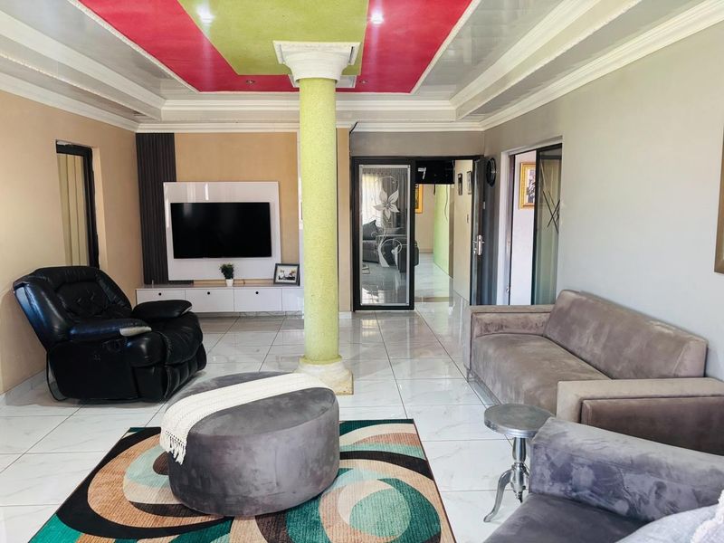 Spacious living room featuring polished tile flooring, a central structural column, and a custom built-in media unit with a recessed ceiling design.