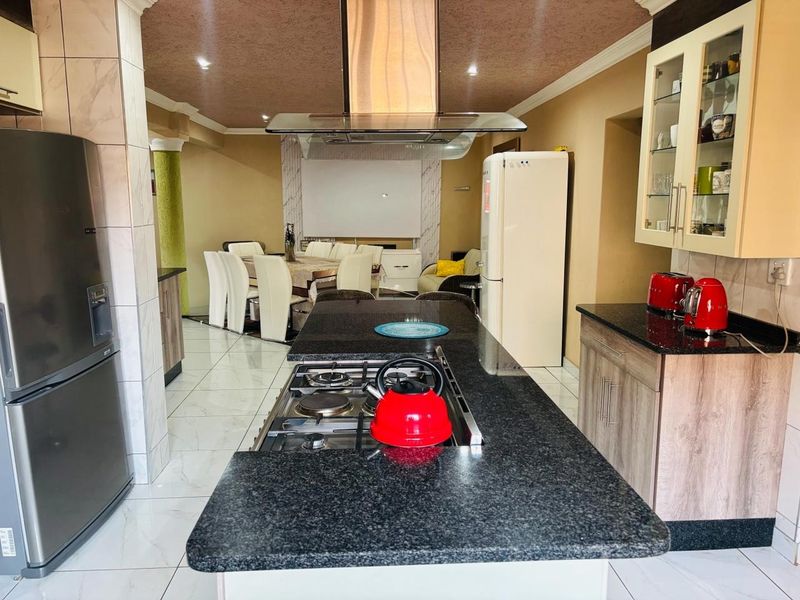 Open-plan kitchen and dining area featuring a central island with a built-in gas hob, granite countertops, and ample cabinetry.