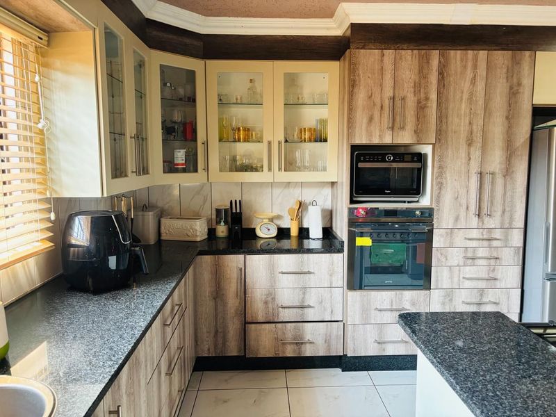 A well-maintained kitchen featuring wood-look cabinetry, granite countertops, and integrated appliances including a built-in oven and microwave.