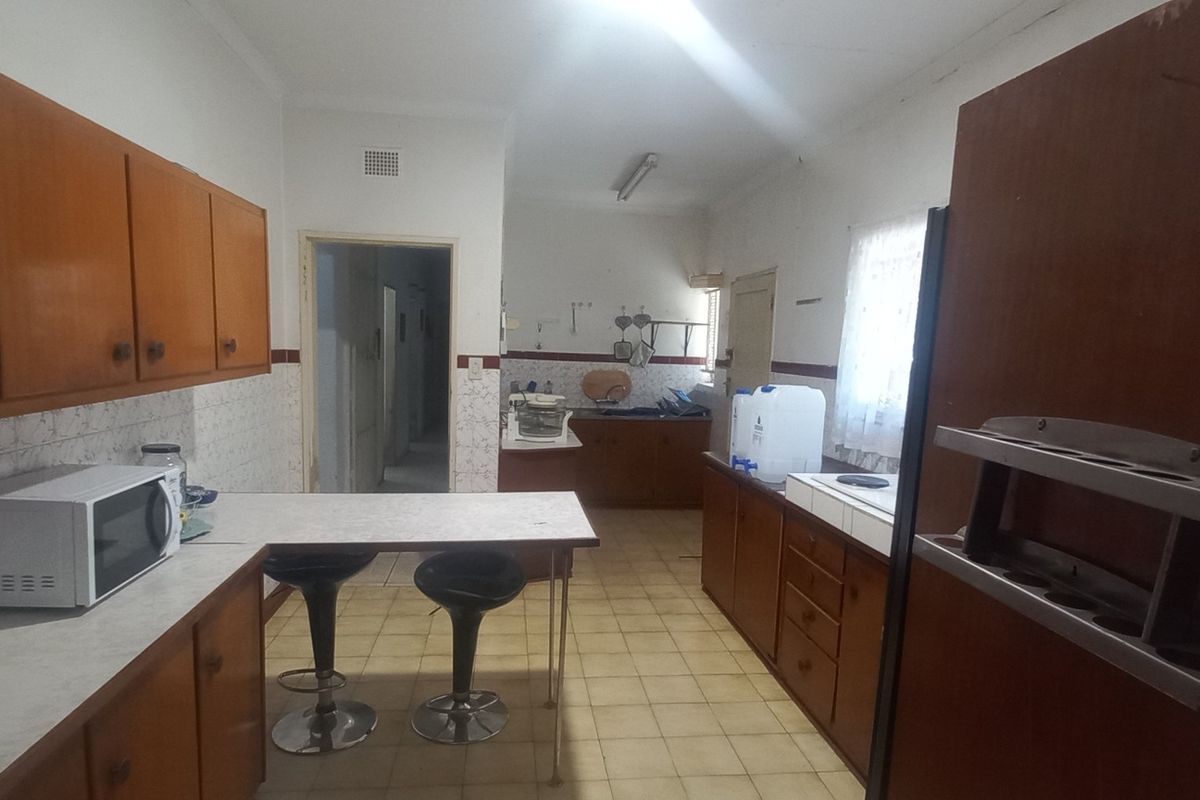 A dated kitchen featuring wooden cabinetry, laminate countertops, and tiled flooring, offering significant potential for modernization and renovation.