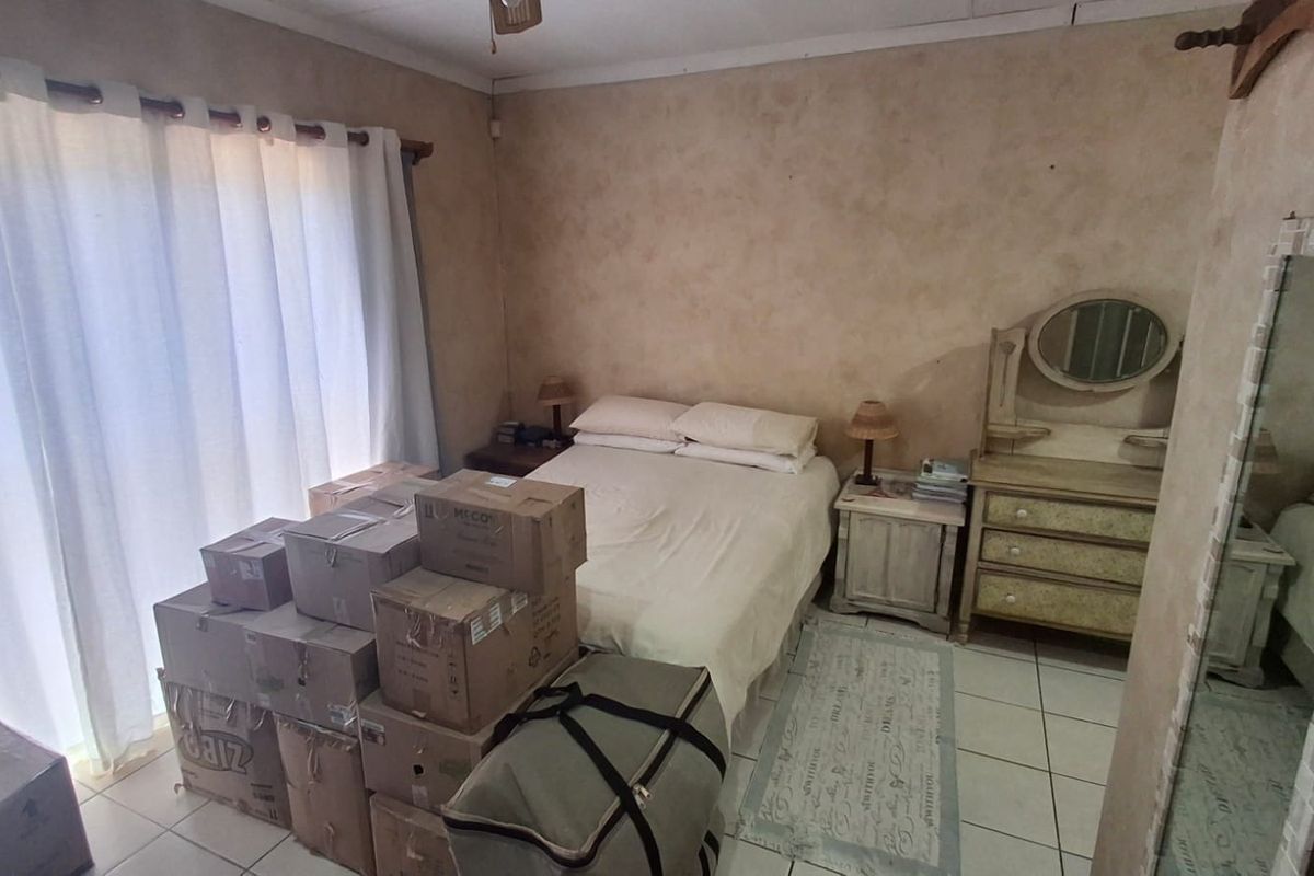 A bedroom featuring tiled flooring and a sliding glass door providing natural light. The space requires cosmetic updates to the wall finishes.