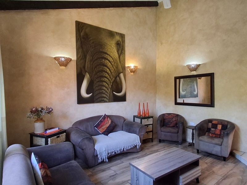 A living room featuring textured walls, exposed ceiling beams, tiled flooring, and an arched entryway leading to adjacent spaces.