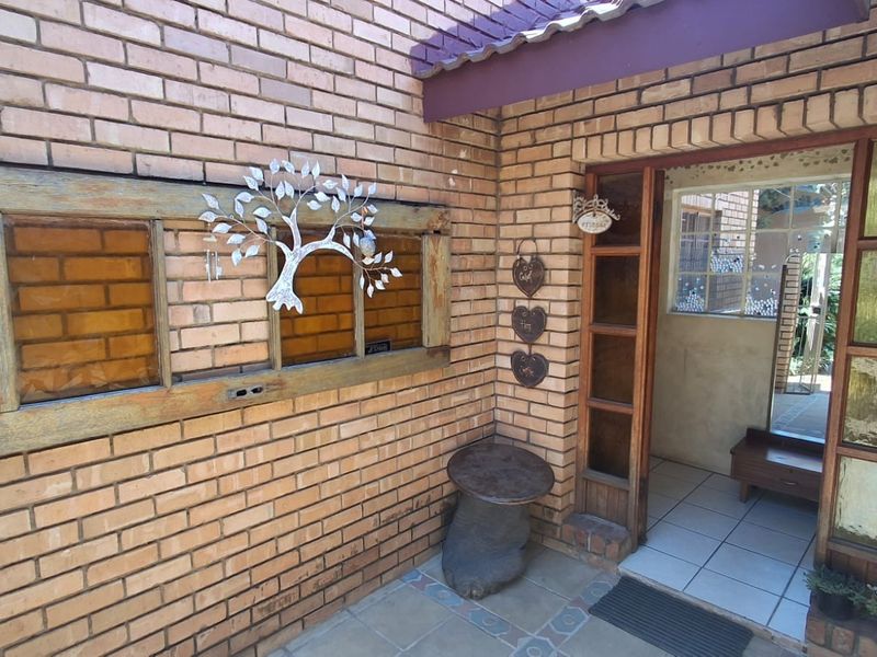 A rustic entrance area featuring exposed brickwork, tiled flooring, and timber-framed windows and door, providing a warm and welcoming access point to the home.