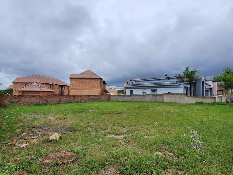 A vacant residential plot featuring a grass lawn and perimeter boundary walls, situated in a developed neighborhood.