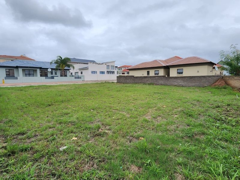 A vacant residential plot of land enclosed by brick boundary walls, situated in a developed suburban neighborhood.