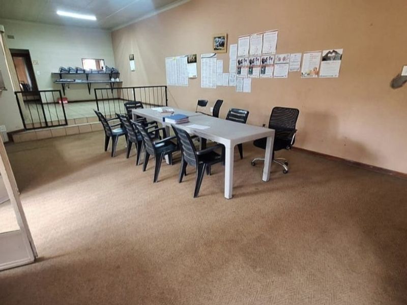 Spacious living area featuring a raised platform with built-in shelving, metal balustrade, and carpeted flooring, offering potential for versatile use.