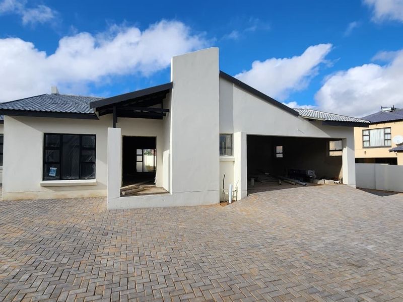 Front elevation of a townhouse under construction, featuring a paved driveway, double garage, and modern architectural lines.