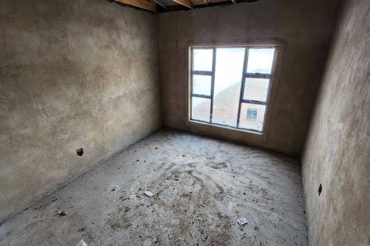 An unfinished bedroom space featuring raw plastered walls, exposed concrete flooring, and an aluminium window frame, ready for final interior finishes and flooring installation.