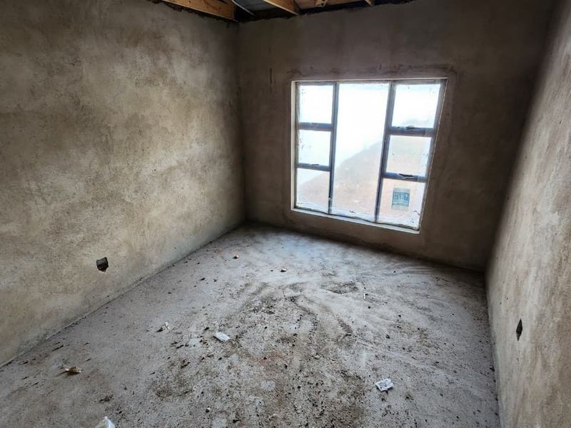 An unfinished bedroom space featuring raw plastered walls, exposed concrete flooring, and an aluminium window frame, ready for final interior finishes and flooring installation.