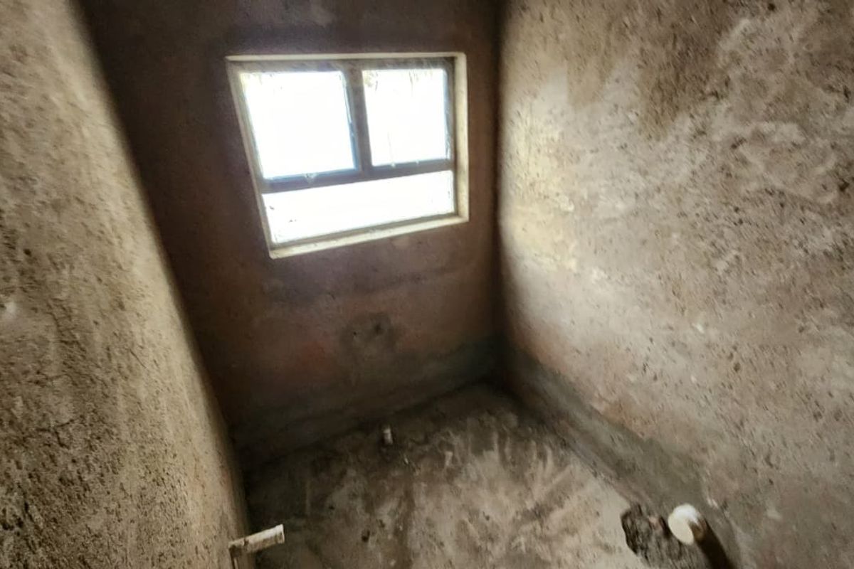 An unfinished bathroom space in shell condition, featuring exposed plumbing rough-ins and raw plaster walls, ready for final finishes and fixtures.