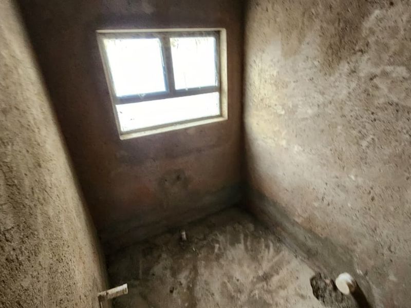 An unfinished bathroom space in shell condition, featuring exposed plumbing rough-ins and raw plaster walls, ready for final finishes and fixtures.