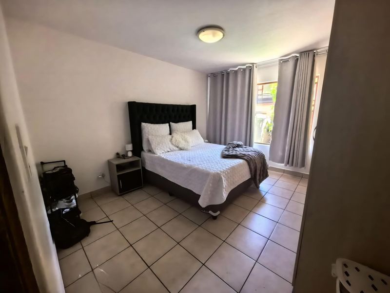 A functional bedroom featuring tiled flooring and natural light through a window with curtains.