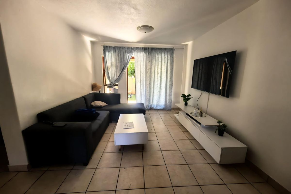 A functional living room featuring tiled flooring and a sliding glass door providing access to the exterior.