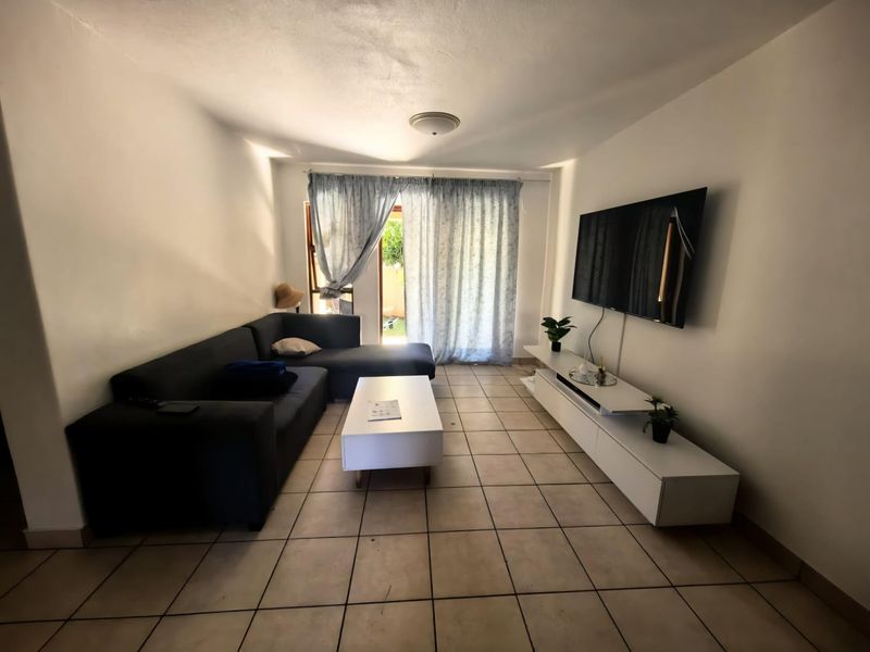 A functional living room featuring tiled flooring and a sliding glass door providing access to the exterior.