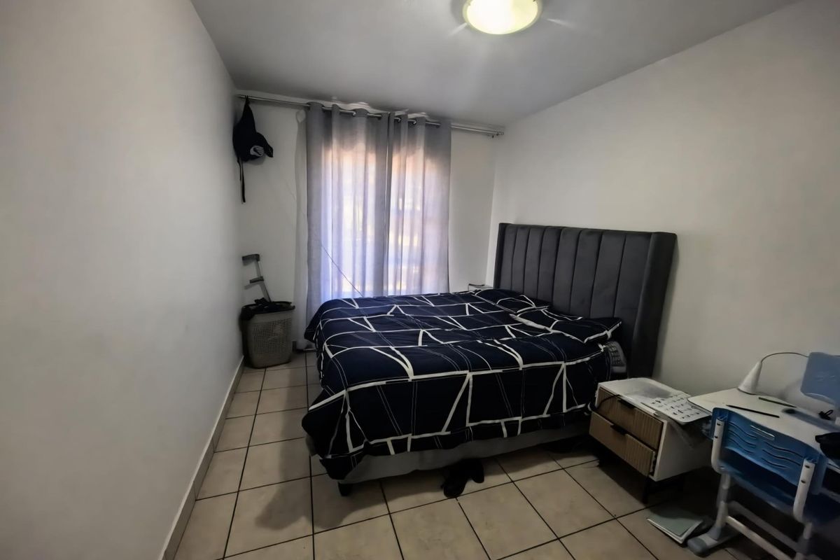 A functional bedroom featuring tiled flooring, a ceiling light fixture, and a curtain rail, providing a neutral base for personalization.