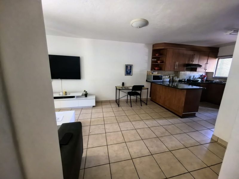 Open-plan living area featuring tiled floors and a functional kitchen with wood cabinetry and granite countertops.