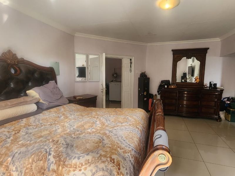 Spacious bedroom featuring tiled flooring and coved ceiling details, offering a functional layout with direct access to an adjoining room.