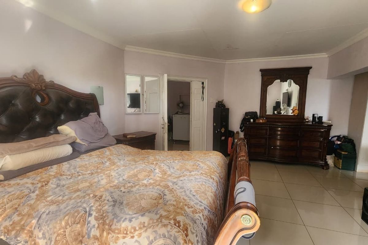 Spacious bedroom featuring tiled flooring and coved ceiling details, offering a functional layout with direct access to an adjoining room.