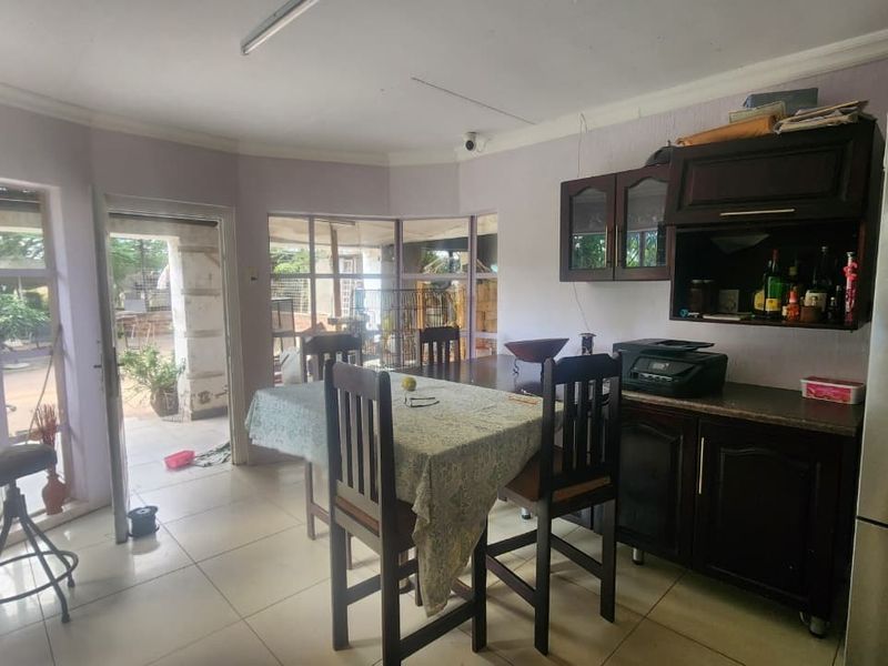 Open plan living and dining area featuring tiled floors, built-in cabinetry, and direct access to the patio through glass sliding doors.