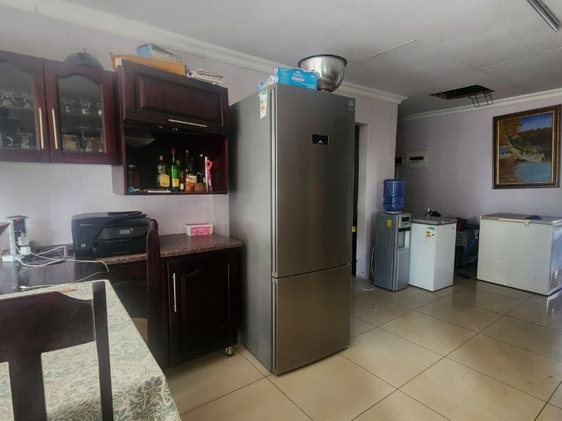 A kitchen area featuring dark wood cabinetry and tiled flooring, currently showing signs of wear including a damaged ceiling section.