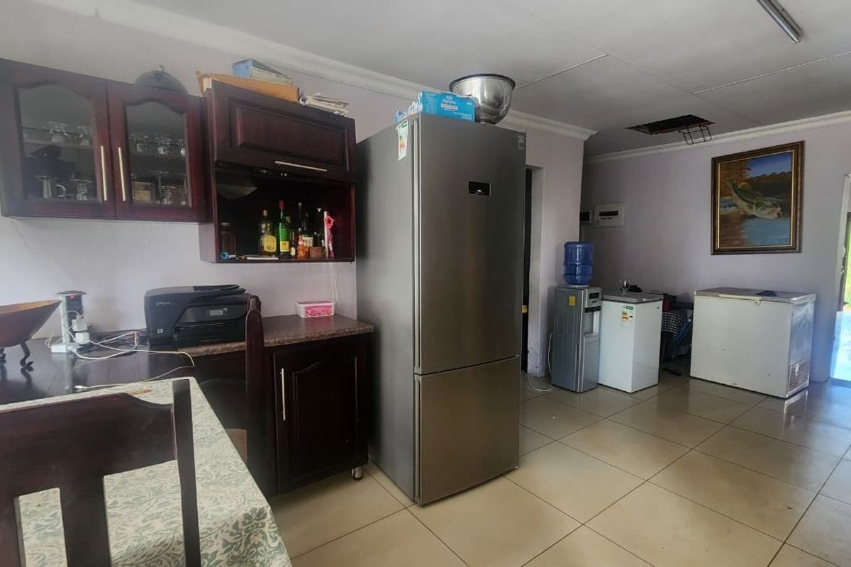A kitchen area featuring dark wood cabinetry and tiled flooring, currently showing signs of wear including a damaged ceiling section.