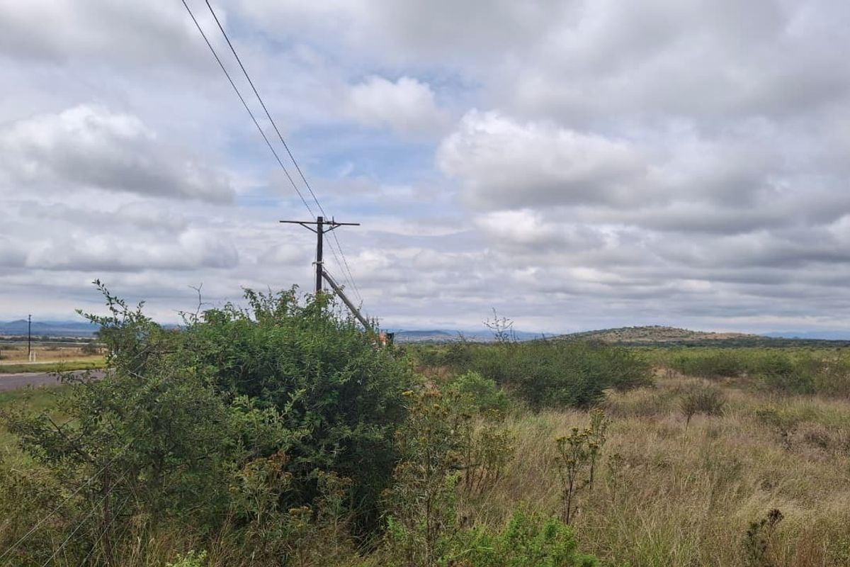 A view of the vacant residential land featuring natural vegetation, open landscape, and existing utility infrastructure including a power pole.