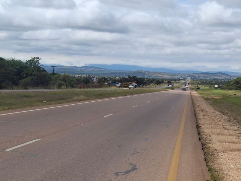 A view of the public asphalt road and surrounding landscape, providing access to the vacant residential land.