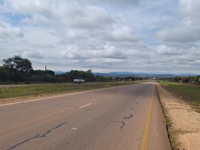 A view of the paved road and surrounding landscape, showing the approach to the property location.