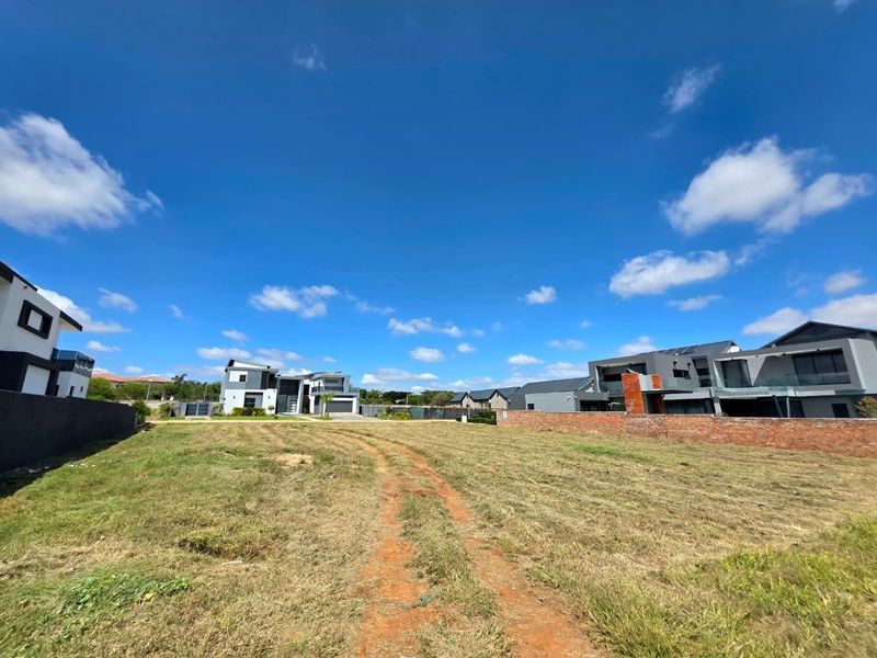 A vacant residential plot of land situated in a developed estate, featuring clear boundaries and surrounding modern residential properties.