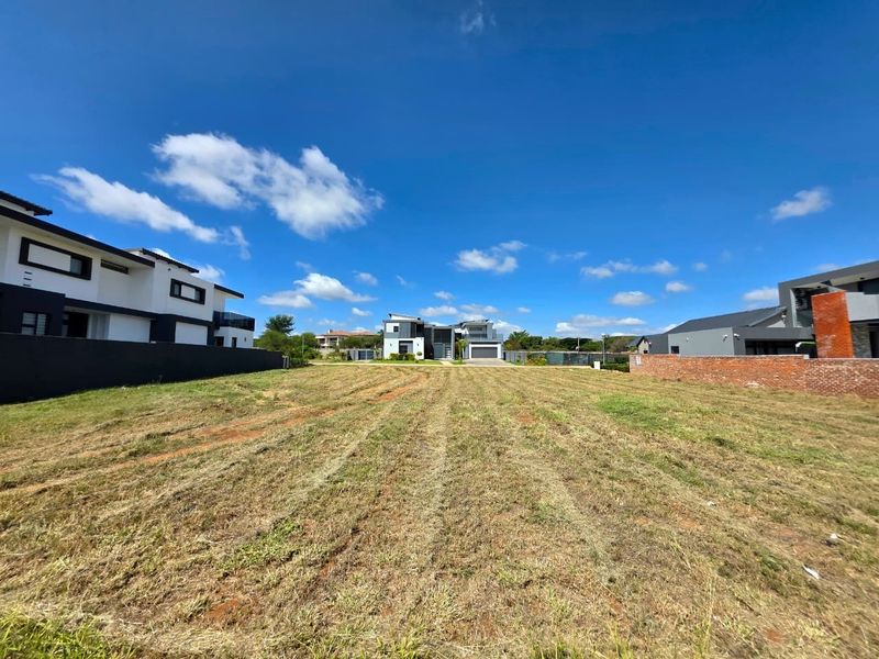 A vacant residential plot of land situated in a developed neighborhood, featuring established boundary walls and clear access for future construction.