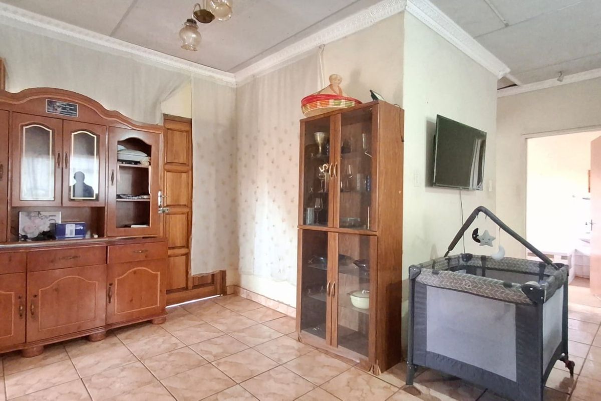 A living area featuring tiled flooring and decorative ceiling cornicing, providing a functional space with potential for cosmetic updates.